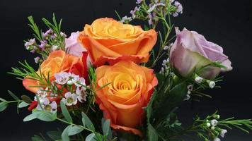 lapso de tempo de abertura para morrer rosas laranja e roxas e flores de cera em fundo preto em 4k video