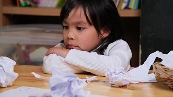 Upset little girl making a colorful drawing at home and crumpled the paper on desk. Girls who are bored with online learning and homework during the coronavirus pandemic. video
