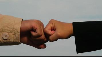 Close-up of young businessman and businesswoman making fist bump on sky background. Business success and teamwork concept. video