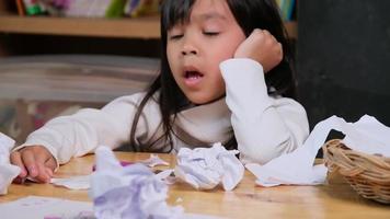 menina chateada fazendo um desenho colorido em casa e amassou o papel na mesa. meninas que estão entediadas com aprendizado on-line e lição de casa durante a pandemia de coronavírus. video