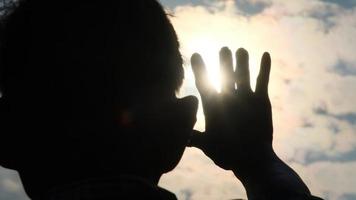 silueta de un hombre mayor que llega a la luz del sol de la tarde. manos de un anciano feliz al atardecer. video