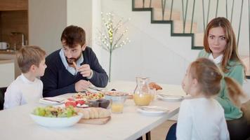 jovem família feliz falando enquanto toma café da manhã na mesa de jantar no apartamento video