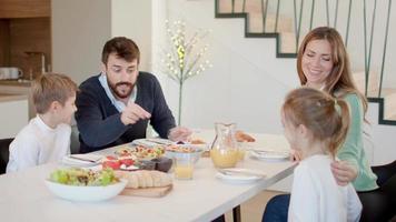 jovem família feliz falando enquanto toma café da manhã na mesa de jantar no apartamento video