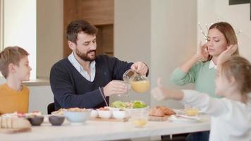 Young happy family talking while having breakfast at dining table at apartment video