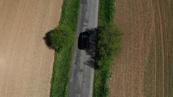 Drone follows a car on road with trees in 4K video