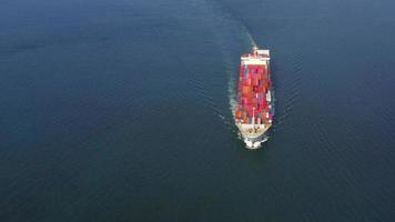 Aerial in front of smart cargo ship carrying container and running  near international custom sea port for export cargo.