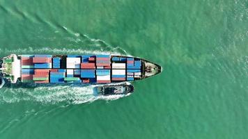 Aerial top view of cargo maritime ship with contrail in the ocean ship carrying container and running for export  concept technology freight shipping by ship smart service video