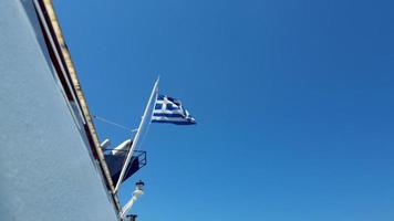 Greek flag waving in the back of a Ferry in the Aegean Sea against a cloudy sky. photo