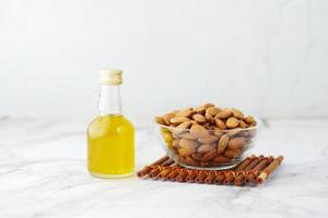 Almond oil in bottle and nut in a bowl on table with copy space photo