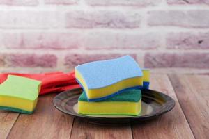 sponge , rubber gloves and colorful plate on pink photo