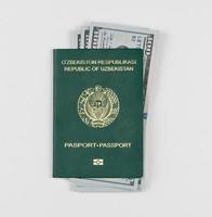 pasaporte de uzbekistán con dólares americanos sobre fondo blanco, aislado. vista superior