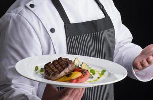 chef in uniform serves a dish in a plate photo