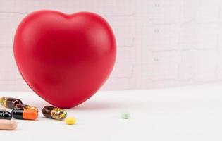 Toy heart with pills on electrocardiogram background. Concept healthcare. Cardiology - care of the heart photo