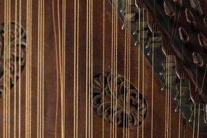 ancient Asian stringed musical instrument on black background with backlight. the similarity of the harp and psaltery. closeup photo