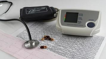 modern electric tonometer and a stethoscope on a cardiogram chart. household blood pressure monitor photo