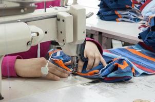 seamstress on the machine sews clothes at a garment factory photo