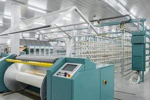 el hilo textil en la máquina de envolver se atornilla en el eje grande. maquinaria y equipo en una fabrica textil foto