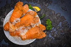 Flathead lobster shrimps on ice, fresh slipper lobster flathead boiled for cooking on white plate lemon parsley in the seafood restaurant kitchen or seafood market, Rock Lobster Moreton Bay Bug photo