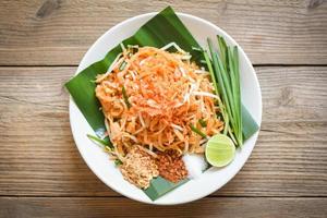 Thai food fried noodle Thai style with prawns bean sprout and garnish peanuts chili powder sugar lemon lime, Stir-fry noodle Pad Thai on plate served on the dining table food - top view photo