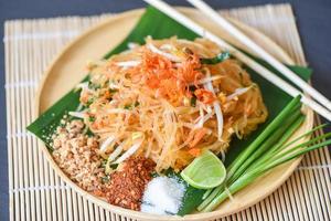 Thai food fried noodle Thai style with prawns bean sprout and garnish peanuts chili powder sugar lemon lime, Stir-fry noodle Pad Thai on plate served on the dining table food - top view photo