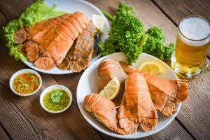 camarones de langosta de cabeza plana servidos en un plato blanco con salsa de mariscos y taza de cerveza, langosta fresca de cabeza plana hervida cocinando con romero de perejil en el restaurante, langosta de roca moreton bay bug foto