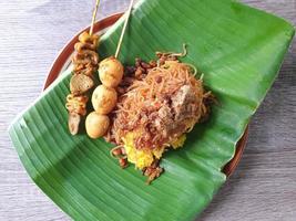 Nasi kuning is a traditional Indonesian dish, served on a banana leaf and plate photo