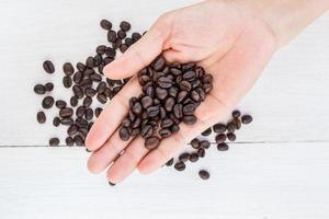 granos de café en la mano contra el fondo del café foto