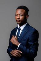 Young handsome African man wearing formal business suit looking at camera isolated on studio gray background photo