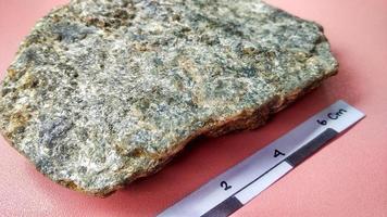 Schistmica metamorphic rock foliated structure on pink background. With quartz, muscovite, garnet, chlorite, calcite, apatite on Melange tectonic zone, Indonesia. Ophiolite area photo