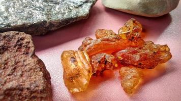 Resin sap is a natural sap from the Agathis borneensis tree, yellow light from central java, Indonesia. Isolated with scistmica, napal and chert, marl from geological collection rock, pink background.