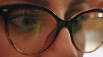 Businesswoman working at night looking at monitor, reflections in eyeglasses. video