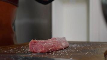 Chef applying pepper on raw piece of steak. video