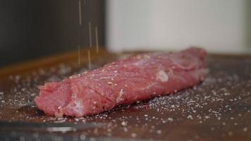 Würzen von rohem Fleisch auf dem Zubereitungstisch. video