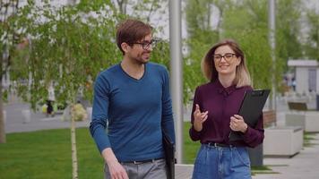 Man and woman walk outside talking about business. video