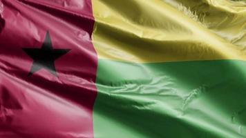 guinea-bissau-flagge weht langsam auf der windschleife. das guinea-bissau-banner, das sich sanft im wind bewegt. voll ausfüllender Hintergrund. 20 Sekunden Schleife. video