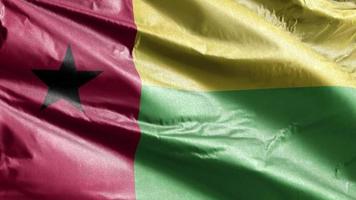 guinea bissaus textilflagga långsamt viftande på vindslingan. Guinea-Bissaus banderoll svajar smidigt på vinden. tyg textilvävnad. full fyllning bakgrund. 20 sekunders loop. video