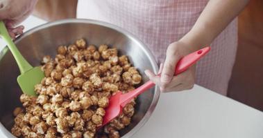 les femmes mélangent du pop-corn au caramel dans le bol de cuisson, au ralenti, 4k video