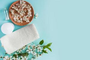 Spa and relaxation accessories on blue background. Aromatic oil, towel, candle and flowers. photo