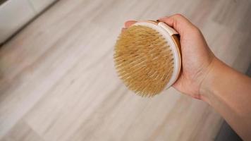 Female hand is holding hatural wooden body brush. Massage, relax, spa. photo