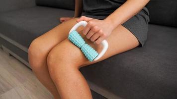 A woman uses a massage roller to massage her legs. Massage for elastic skin photo