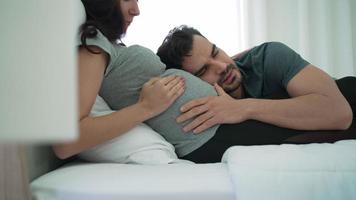 kaukasiska gravida paret ligger tillsammans i sängen video