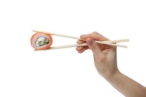 Woman hand holding fresh sushi roll with wooden chopsticks, isolated on white background photo