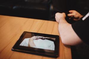 man watching video on tablet how to tie a tie. groom's morning preparation. photo