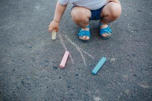 Close up of little girl drawing with chalks on the sidewalk photo