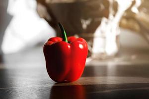 Pimiento rojo fresco sobre una mesa con luz solar desde la ventana de la cocina foto