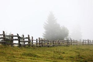 autumn meadow with a old wooden fence on a farm close up, in the Smoky Mountains on a foggy day. travel destination scenic, carpathian mountains photo
