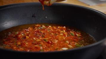 Zubereiten einer Sauce aus Tomatenmark und Zwiebel in der Pfanne. video