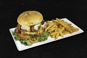 hamburguesa doble con papas fritas sobre fondo negro foto