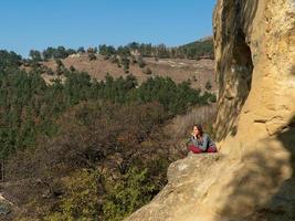 mujer sonriente sentada en una montaña en posición de loto en un día de otoño foto