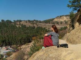 mujer frente al sol en una montaña, vestida con pantalones indios, meditando, retrato en un día de otoño foto